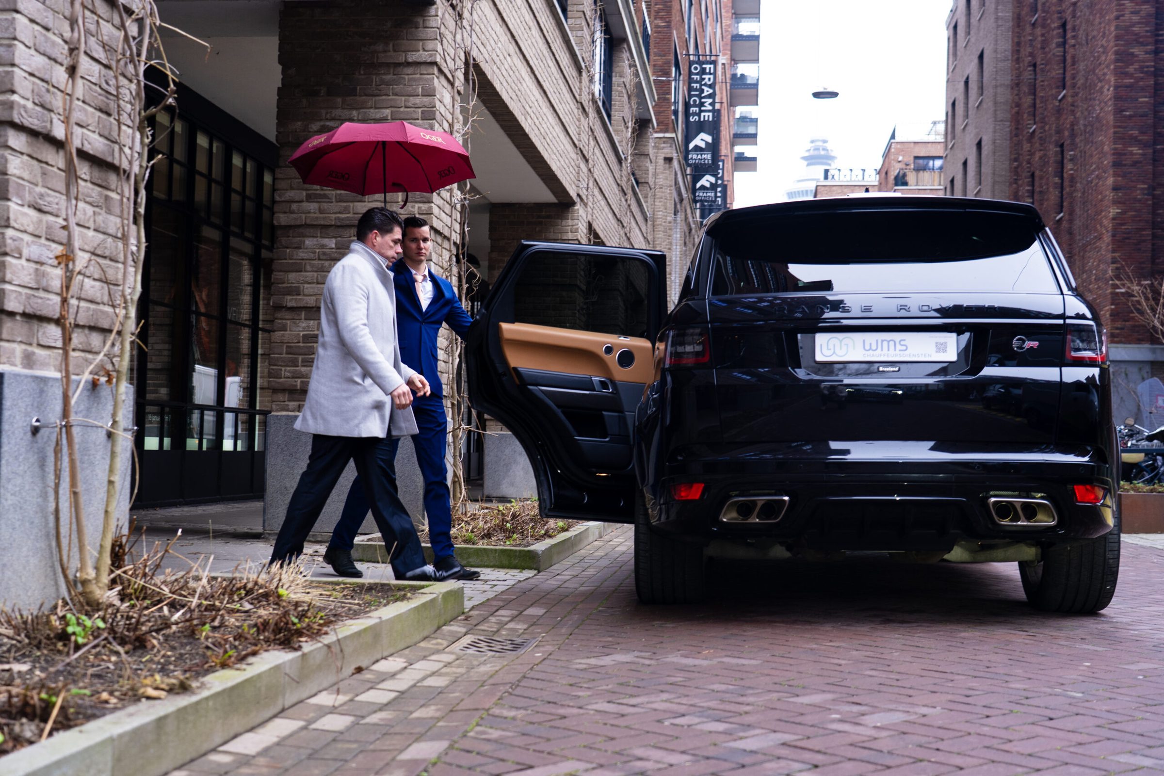 Directiechauffeur in pak bij zakelijke auto in Rotterdam
